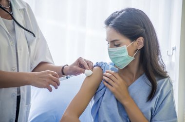 The female doctor vaccinated or  syringe to injection to the young patient put on a mask in the hospital.Medical healthcare concept.